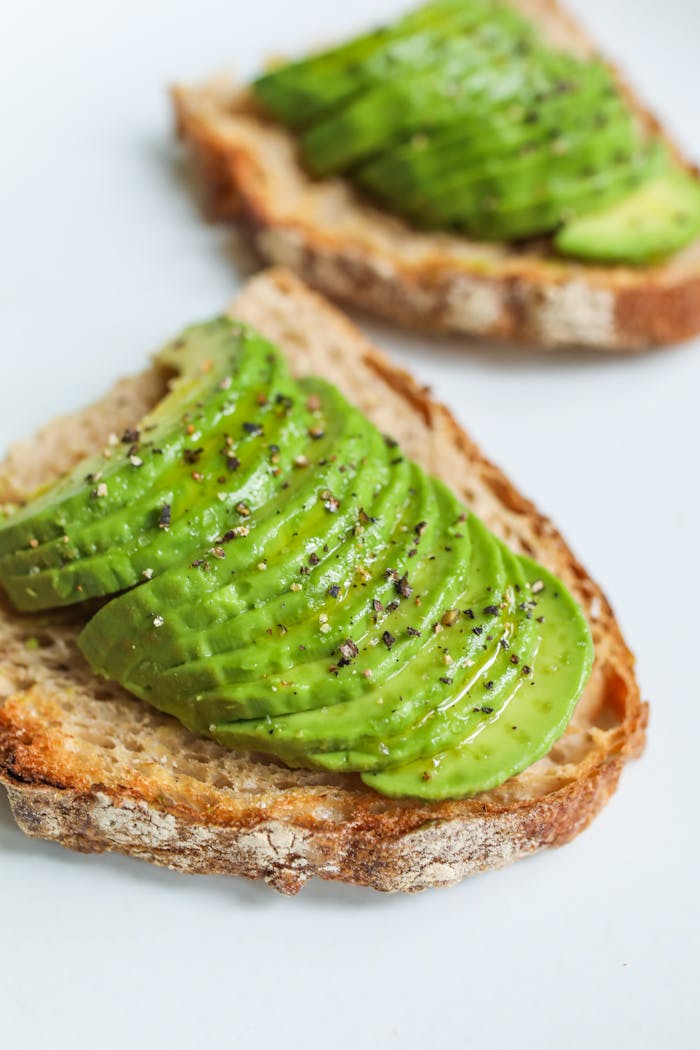 services-06 Sliced avocado atop sourdough bread, seasoned with pepper, photographed for a food photography series.