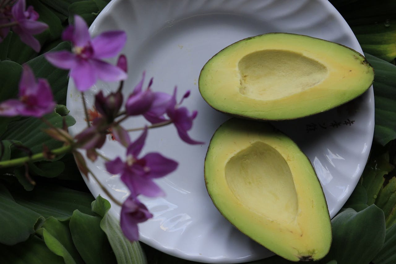 about-us Fresh sliced avocado on white dish with vibrant purple orchids.